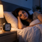 Person lying awake in bed at night with a bedside lamp, unable to sleep